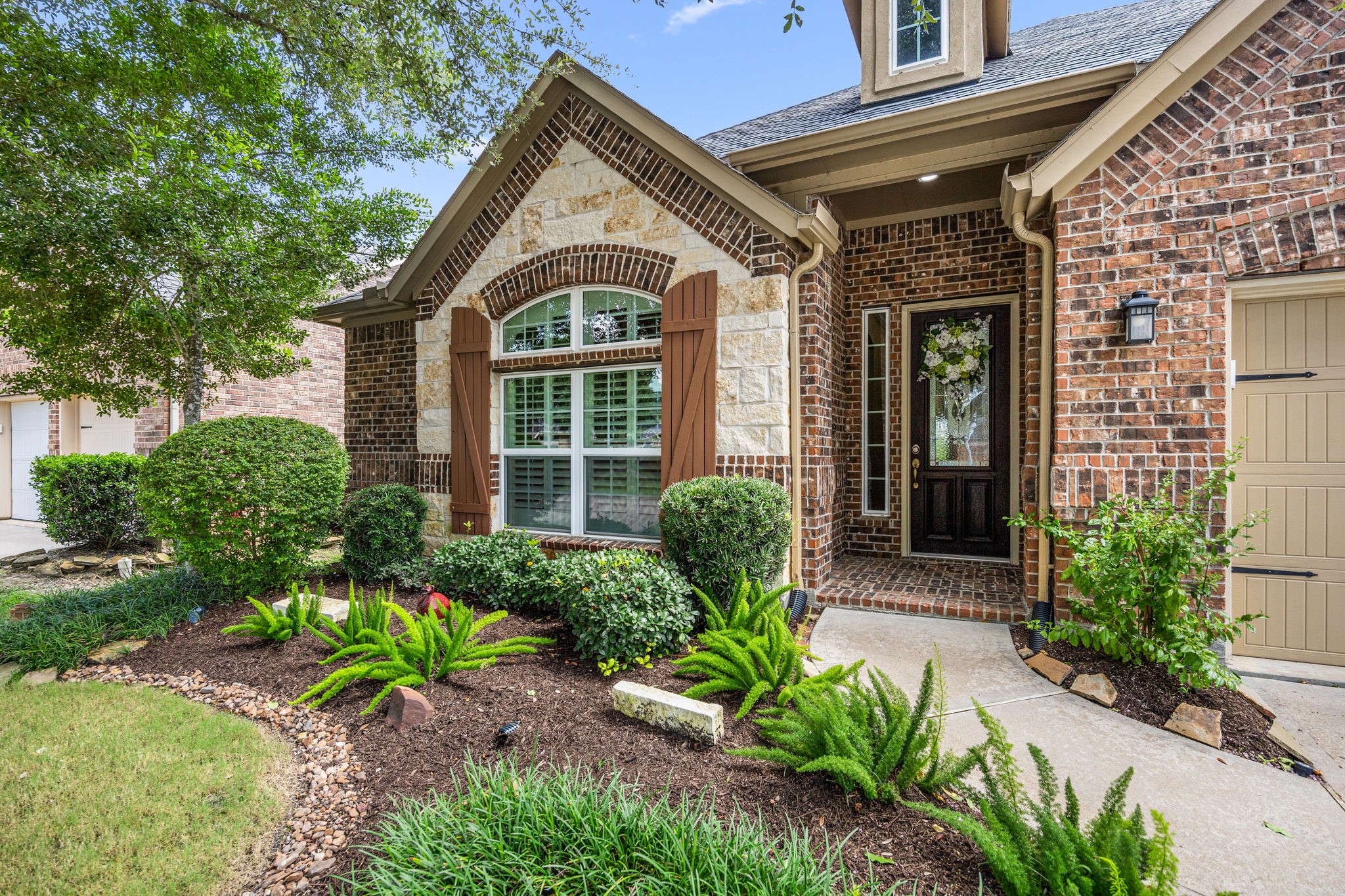 27642 Linden Ridge Lane Fulshear, TX 77441 - Photo 2 of 42 As your guests make their way to the front entrance, they are welcomed by lush landscaping, mature Oak trees, and a charming covered Front Porch with a beautiful brick floor—creating a warm and inviting first impression.