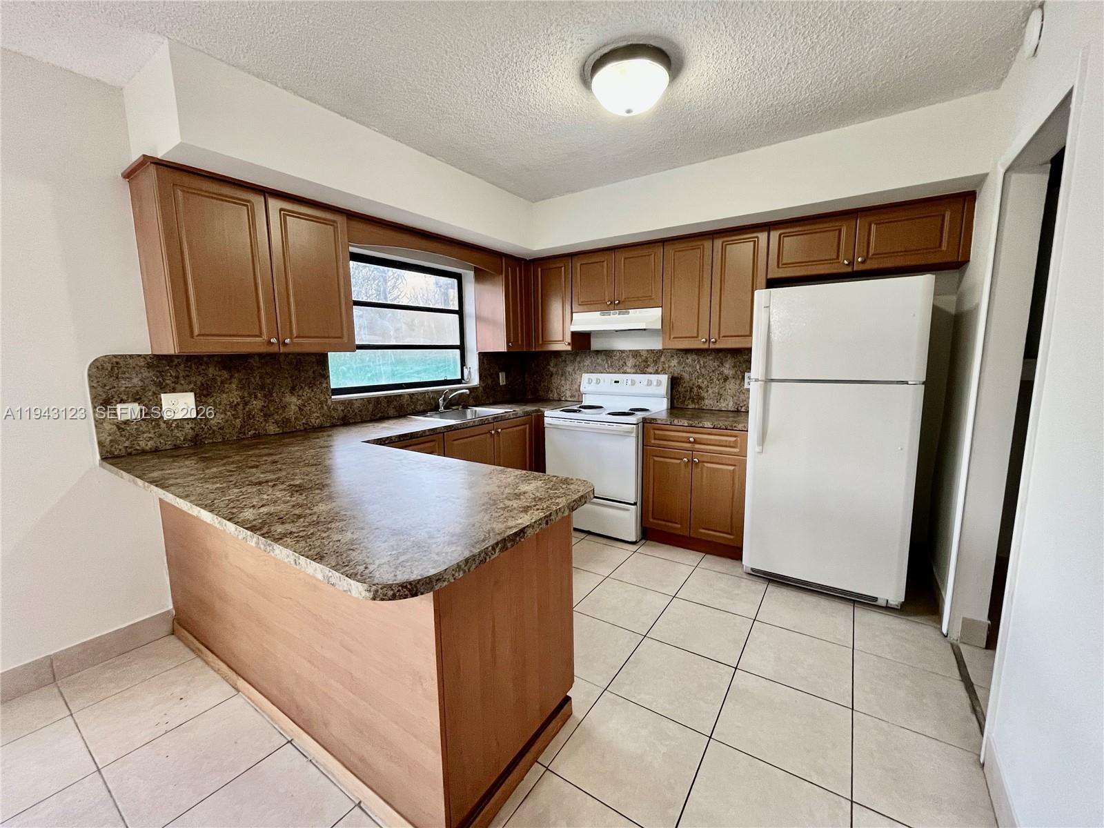 1127 West 37th Street Hialeah, FL 33012 - Photo 8 of 16 a kitchen with stainless steel appliances granite countertop a refrigerator sink and stove