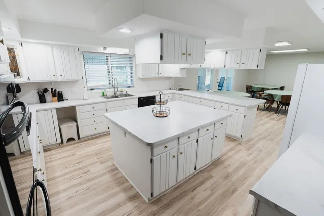a kitchen with a stove a sink a refrigerator and white cabinets with wooden floor