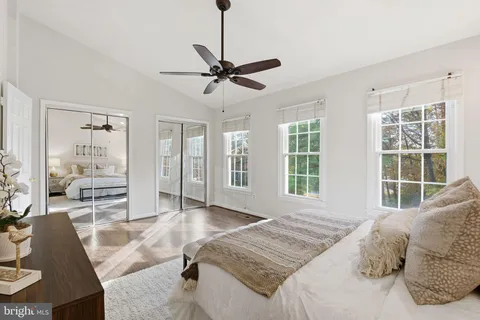 a spacious bedroom with a large bed a chandelier and windows