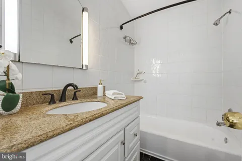 a bathroom with a granite countertop sink a mirror and a bathtub