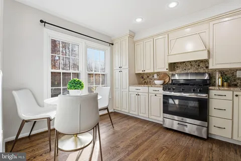 a kitchen with stainless steel appliances a stove a sink a microwave a dining table and chairs