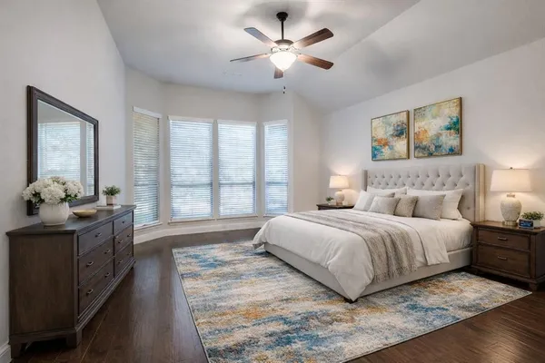 a spacious bedroom with a large bed and a chandelier fan