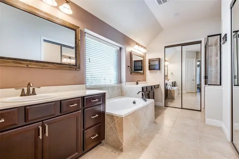 a spacious bathroom with a tub sink and mirror