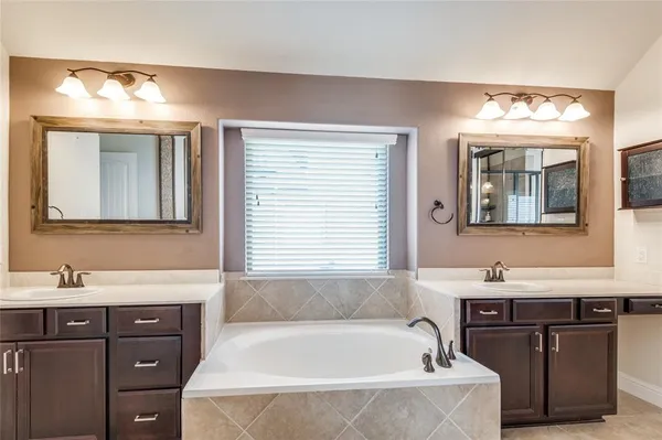 a bathroom with a tub a sink and a mirror