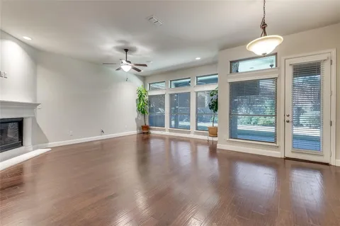 an empty room with wooden floor chandelier and windows