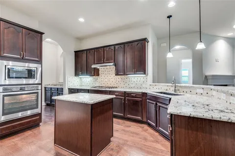 a kitchen with stainless steel appliances granite countertop wooden cabinets a stove and a sink