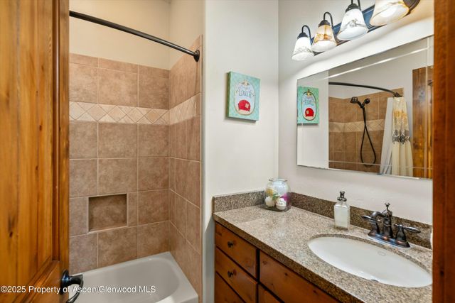 a bathroom with a granite countertop sink a mirror and shower