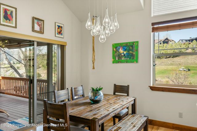a view of a dining room with furniture a chandelier and a window