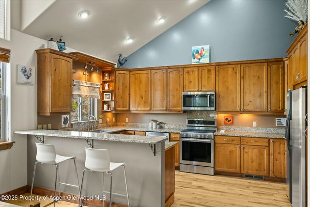 a kitchen with kitchen island granite countertop a stove top oven a sink and cabinets
