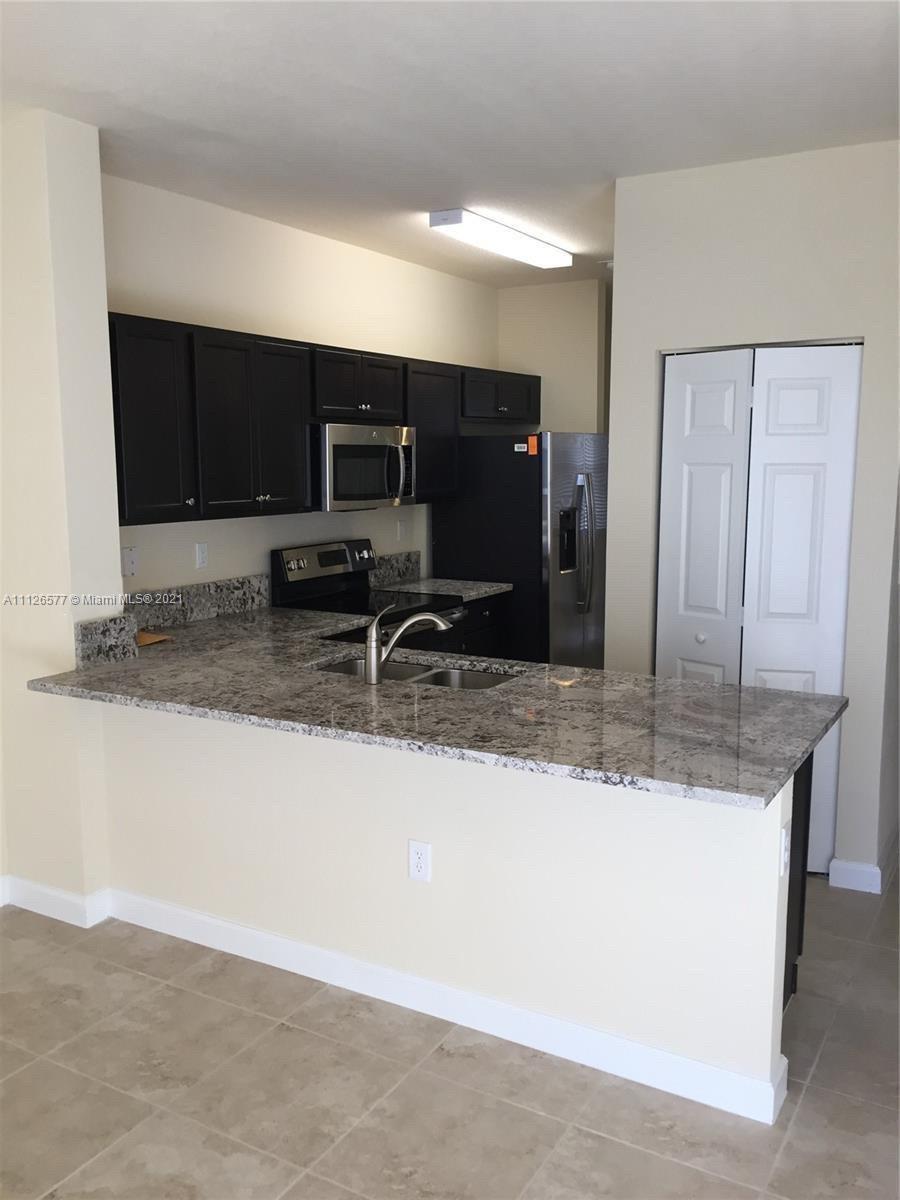 134 Northeast 28th Terrace, Unit 4 Homestead, FL 33033 - Photo 5 of 33 a kitchen with kitchen island granite countertop a sink and a stove top oven
