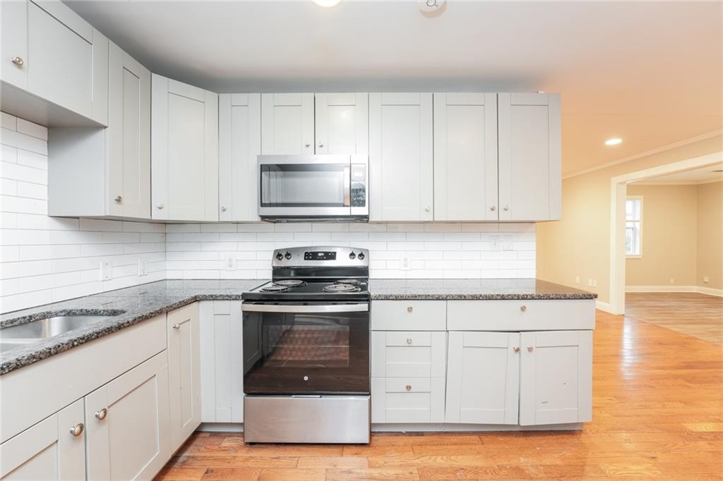 528 Newlin Court Lawrenceville, GA 30046 - Photo 12 of 30 a kitchen with stainless steel appliances granite countertop white cabinets granite counter tops and a hard wood floors