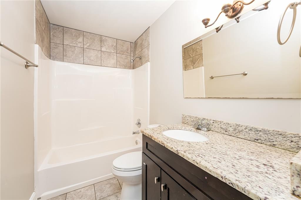 528 Newlin Court Lawrenceville, GA 30046 - Photo 22 of 30 a bathroom with a granite countertop sink a toilet and shower