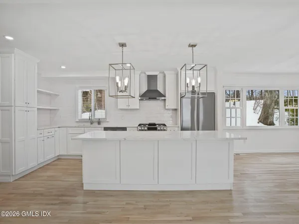 a kitchen with stainless steel appliances kitchen island granite countertop a stove a sink and white cabinets