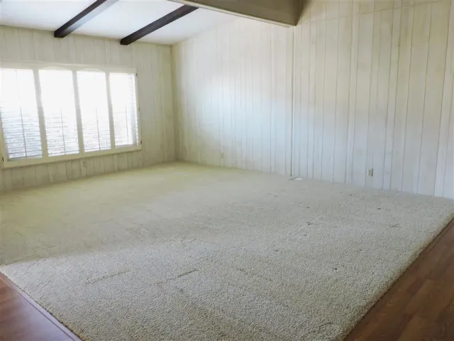 an empty room with wooden floor chandelier fan and windows