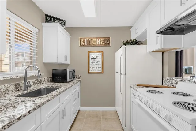 a kitchen with granite countertop a sink stove and refrigerator