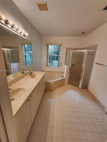 a large bathroom with a tub a sink and a large mirror