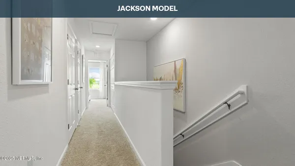 a view of a hallway to an empty room with wooden floor and a bathroom