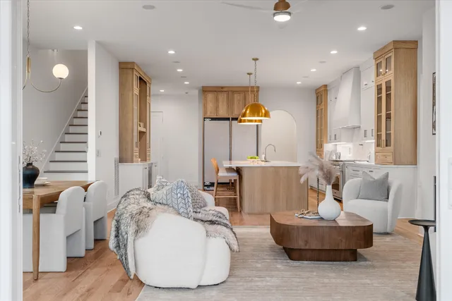 a living room with couches and kitchen view with wooden floor