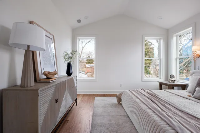 a spacious bedroom with a bed and a dresser next to a window
