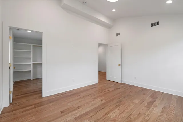 a view of an empty room with wooden floor and closet
