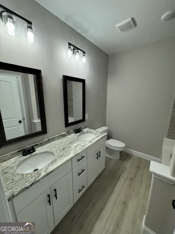 a bathroom with a granite countertop sink mirror and toilet