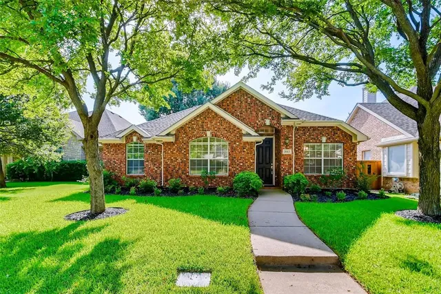 a view of a house next to a big yard and large trees