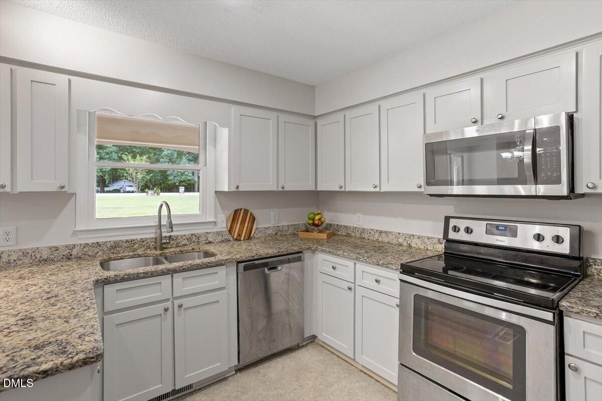 805 Rand Road Garner, NC 27529 - Photo 26 of 38 a kitchen with stainless steel appliances granite countertop a sink stove and microwave