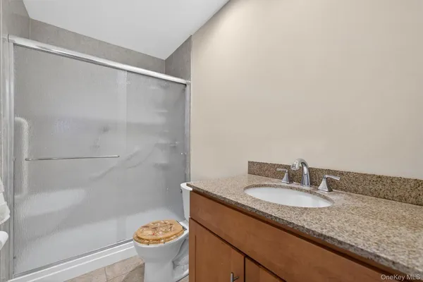 a bathroom with a granite countertop sink a toilet and shower