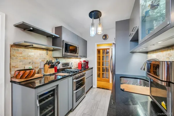 a kitchen that has a lot of cabinets and stainless steel appliances