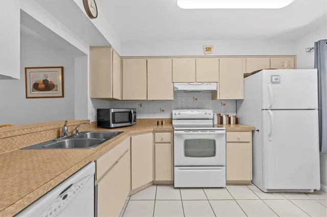 a white kitchen with sink and white stainless steel appliances