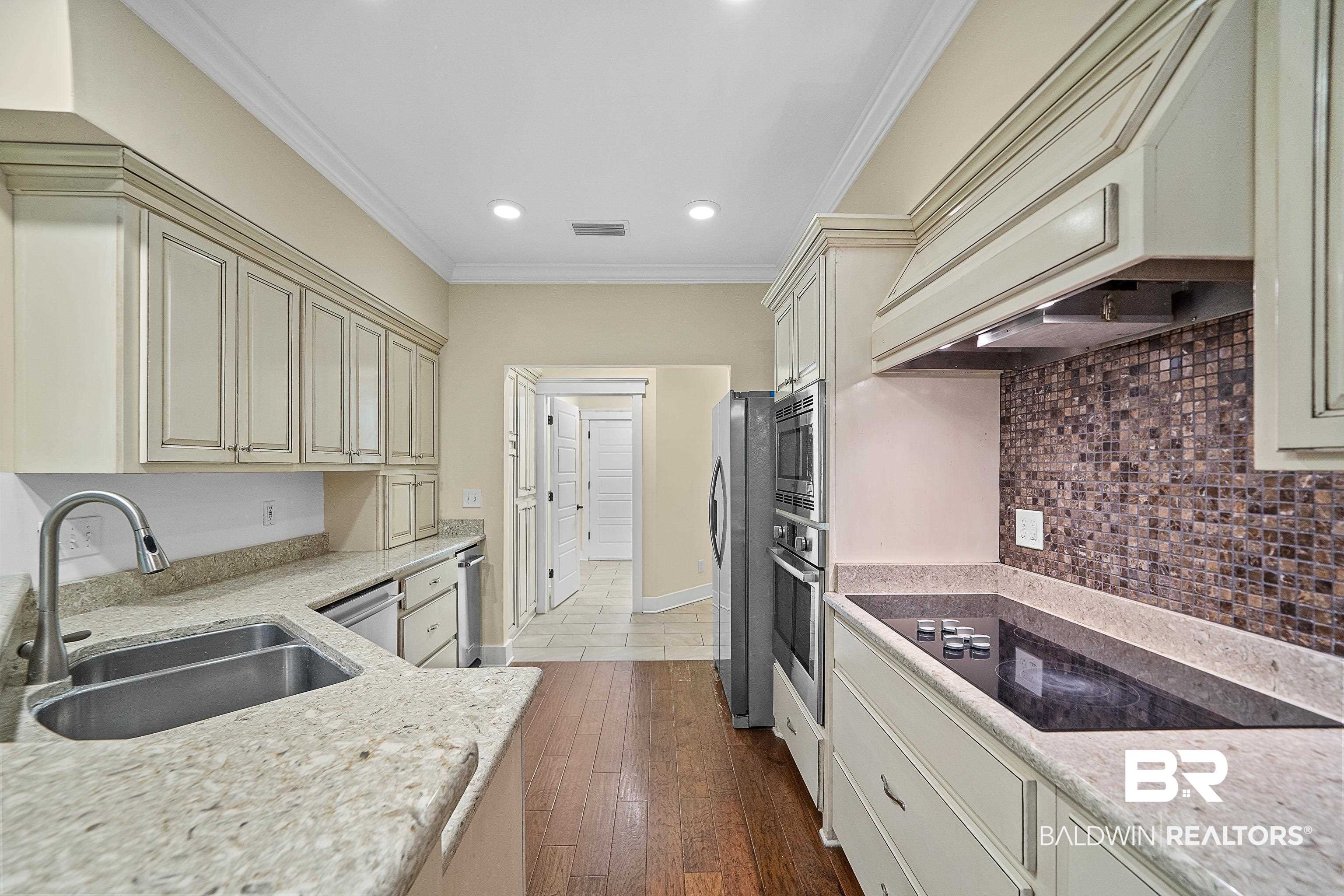 356 Liberty Street Fairhope, AL 36532 - Photo 8 of 39 Kitchen with ornamental molding, cream cabinetry, light stone countertops, premium range hood, and appliances with stainless steel finishes