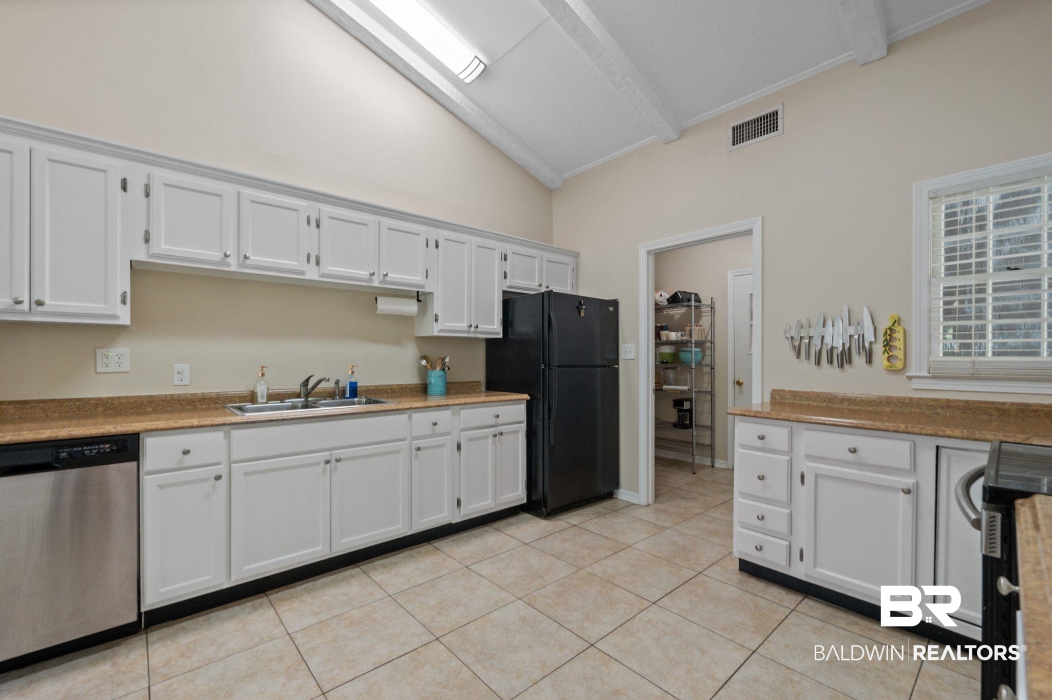 110 Ferncliff Circle Daphne, AL 36526 - Photo 14 of 40 Kitchen with stainless steel dishwasher, a sink, freestanding refrigerator, light tile patterned flooring, and white cabinets