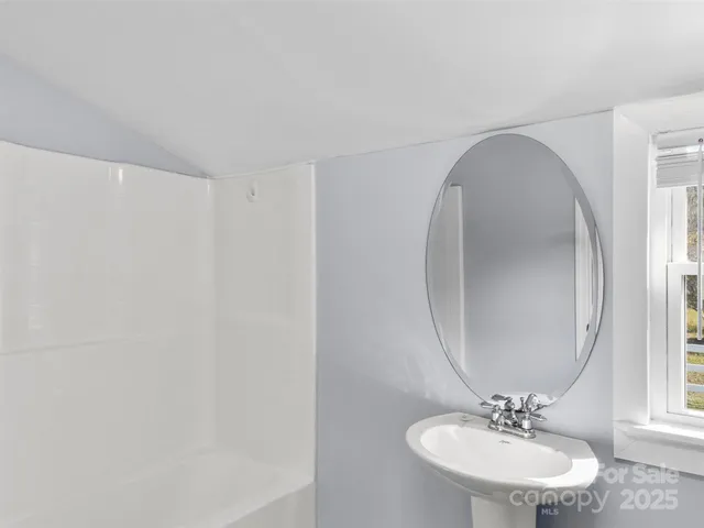a view of an empty room with wooden floor and a ceiling fan