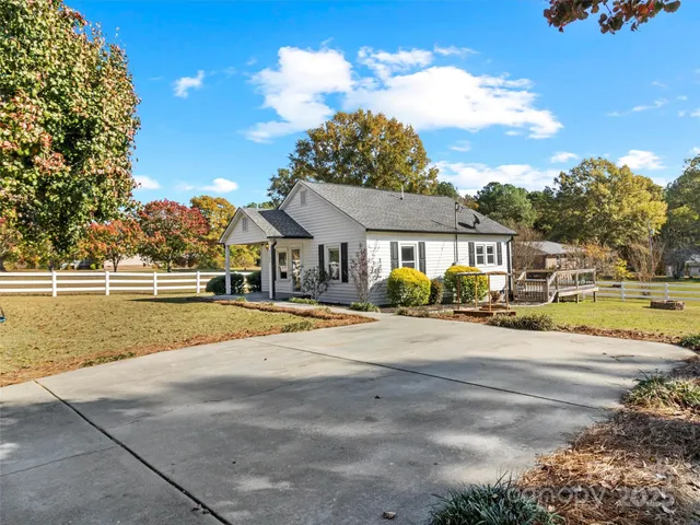 a view of an empty room with wooden floor and a ceiling fan