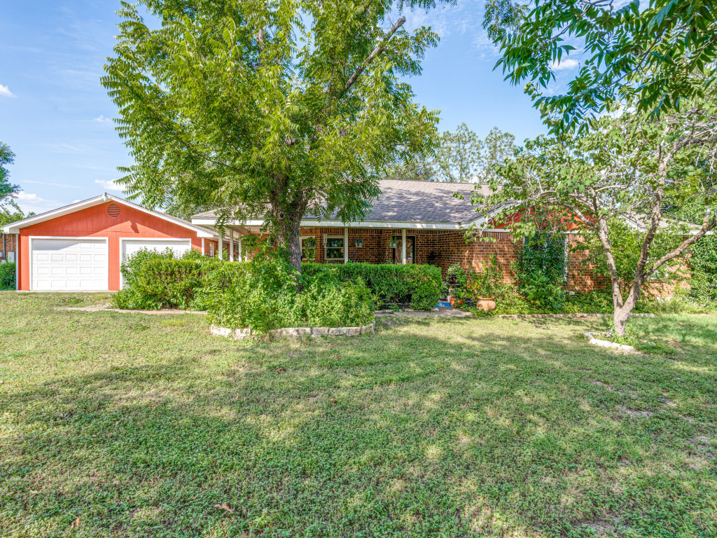 1035 Palomino Road Kyle, TX 78640 - Photo 1 of 13 Mature trees and vibrant landscaping frame this inviting brick home with an attached two-car garage.