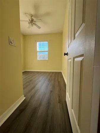 a view of a hallway with wooden floor and a chandelier