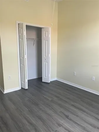 an empty room with wooden floor & closet area