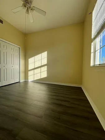an empty room with wooden floor fan and windows
