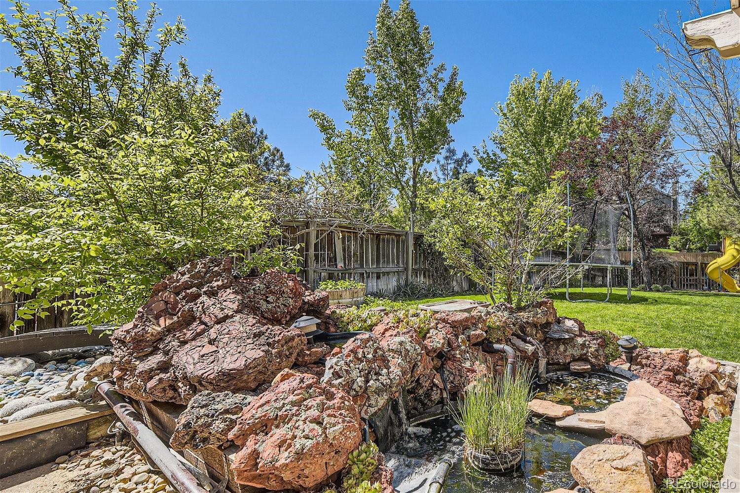 9744 South Castle Ridge Circle Highlands Ranch, CO 80129 - Photo 25 of 28 a view of a backyard with table and chairs plants and large trees