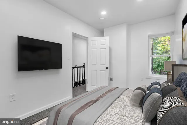 a bedroom with a bed a flat screen tv and a window