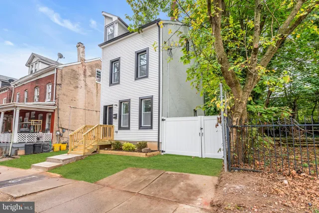 a view of a white house next to a yard and tree
