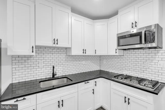 a kitchen with granite countertop white cabinets and stainless steel appliances