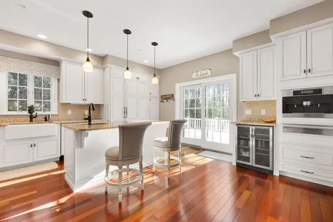 a kitchen with kitchen island granite countertop a stove a sink a dining table and chairs with wooden floor