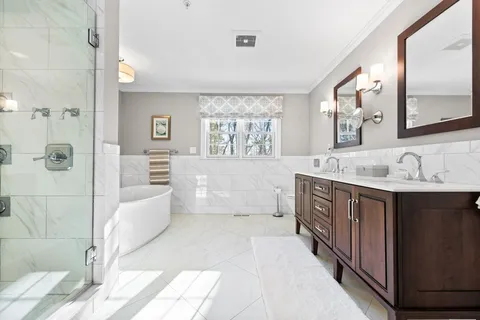 a spacious bathroom with a tub sink and mirror