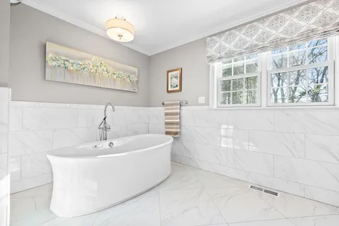 a white bath tub sitting in a bathroom next to a window