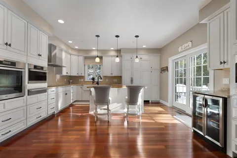 a kitchen with stainless steel appliances granite countertop a stove top oven a sink dishwasher and white cabinets with wooden floor