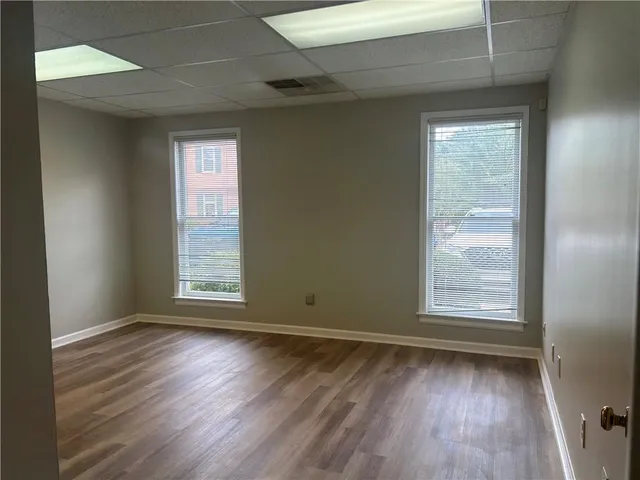 an empty room with wooden floor and windows
