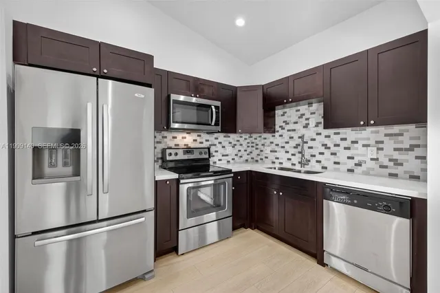 a kitchen with stainless steel appliances wooden cabinets a sink and a refrigerator