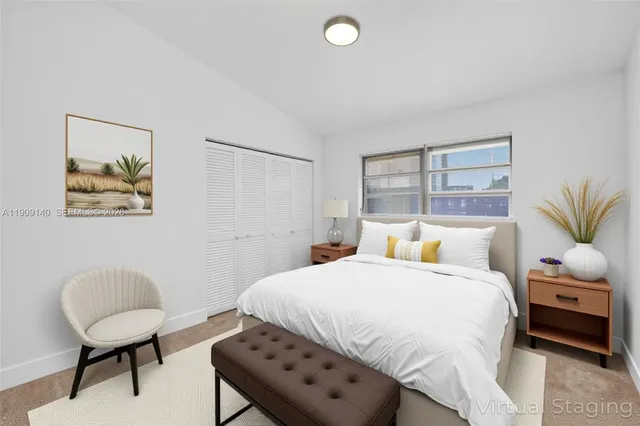 a bedroom with a bed a painting on the wall and a window